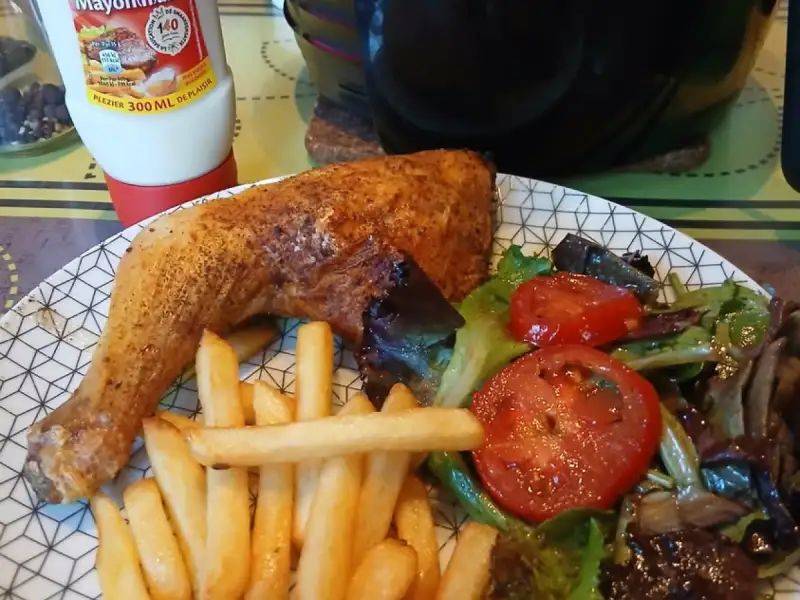 Air fryer chicken legs: a crispy chicken leg with fries and tomato salad on a plate