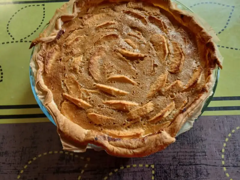 Goudbruine Elzasser appeltaart met schijfjes appel in de room, in een glazen vorm
