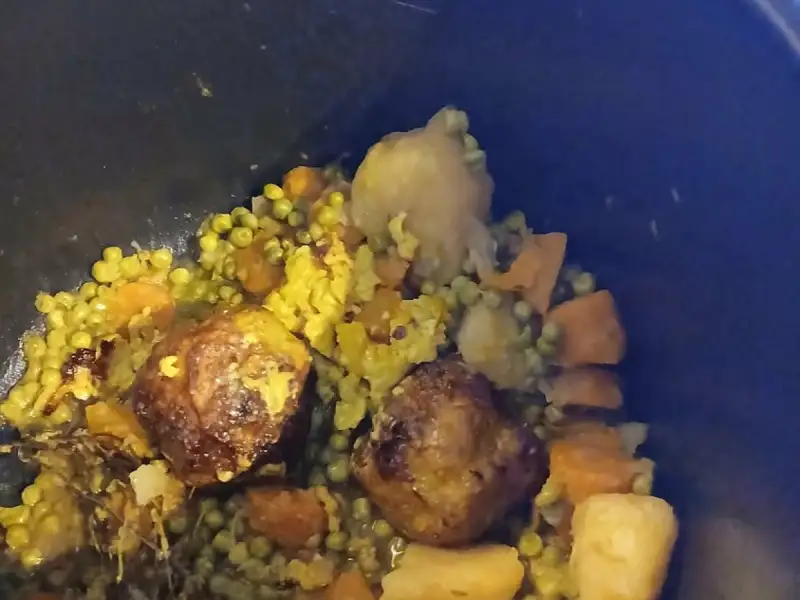 Boulettes aux petits pois, carottes et pommes de terre au curcuma mijotées dans une cocotte noire