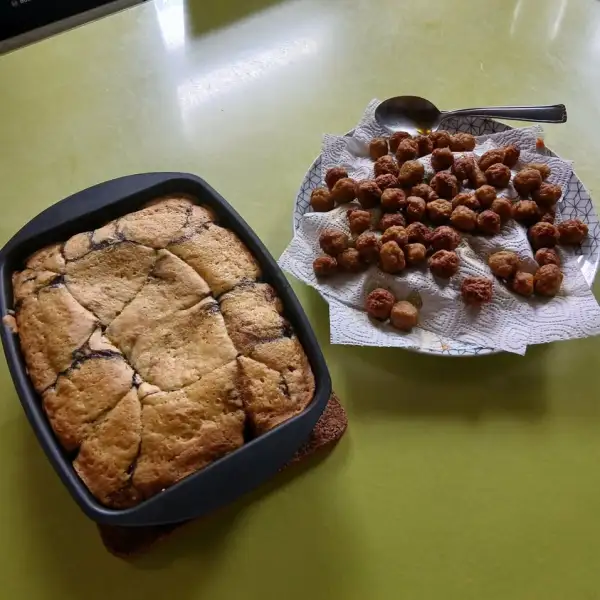 Cake aux cerises doré dans un moule carré, à côté d'une assiette de petites boulettes