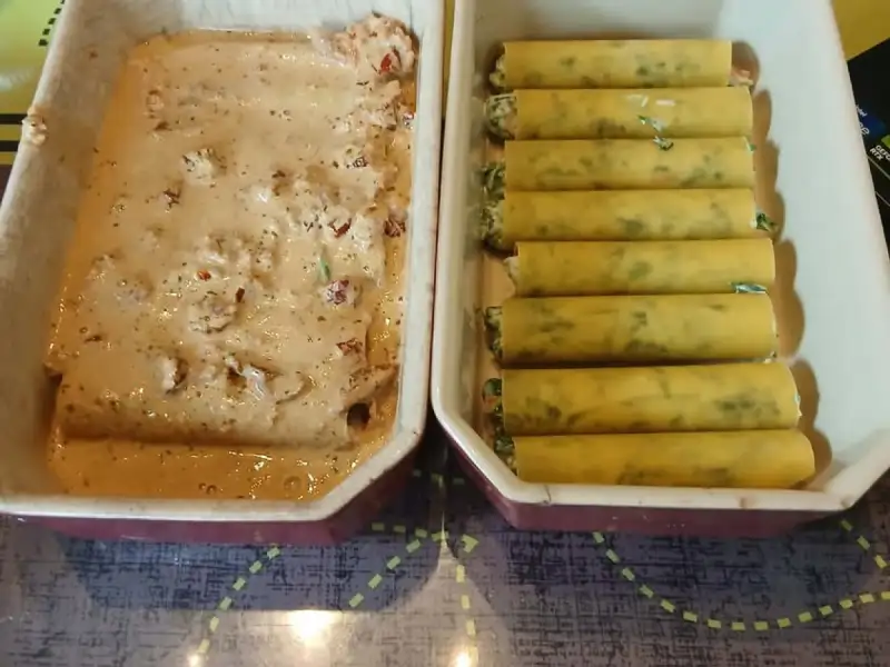 Cannellonis épinards ricotta alignés dans un plat, à côté d'un second plat nappé de sauce crème au saumon et tomates séchées
