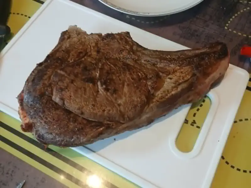 Côte à l'os de bœuf grillée posée sur une planche à découper blanche