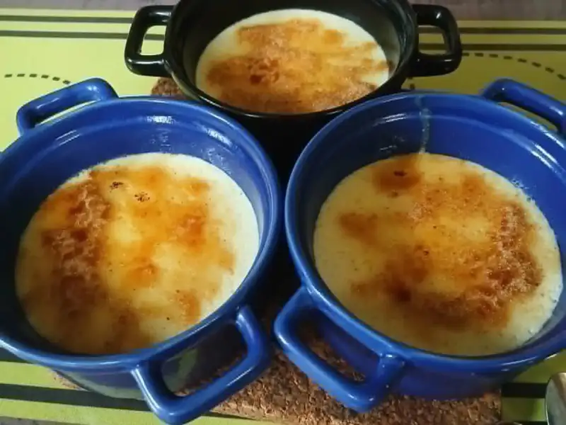 Three caramelized crèmes brûlées in small black and blue ramekins