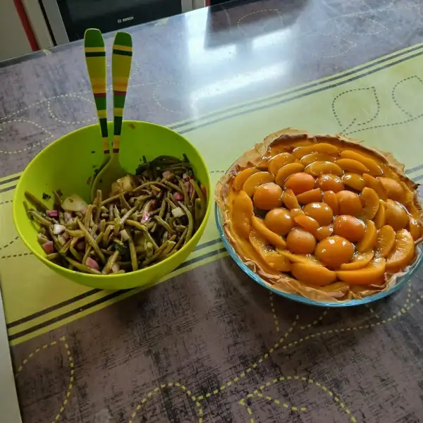 Ensalada de ejotes con cebolla morada y pepino en una ensaladera verde, junto a una tarta de duraznos