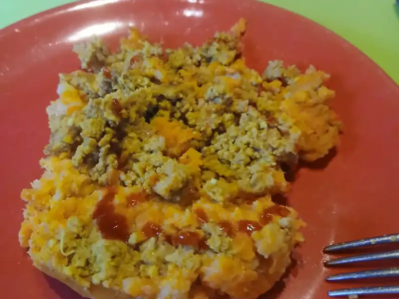 Part de hachis parmentier à la purée de carottes et viande hachée sur une assiette rouge