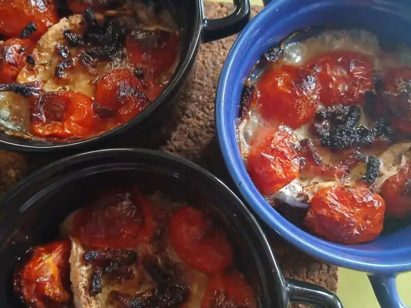 Drei Förmchen mit Hähnchen, gerösteten Kirschtomaten und überbackenem Mozzarella frisch aus dem Ofen