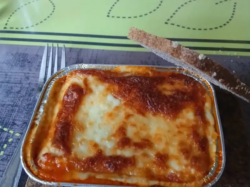 Lasagnes individuelles maison : une barquette en aluminium bien gratinée avec une tranche de pain grillé