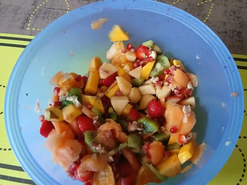 Schüssel mit frischem Obstsalat: Apfel, Kiwi, Melone, Granatapfel, Mango, Orange und Erdbeeren