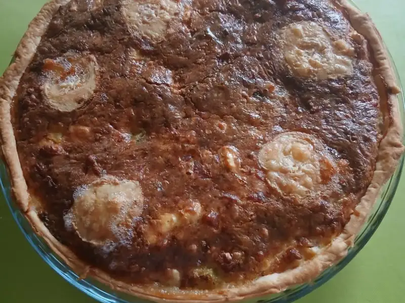 Quiche aux restes du frigo bien dorée avec des rondelles de fromage de chèvre, dans un moule en verre