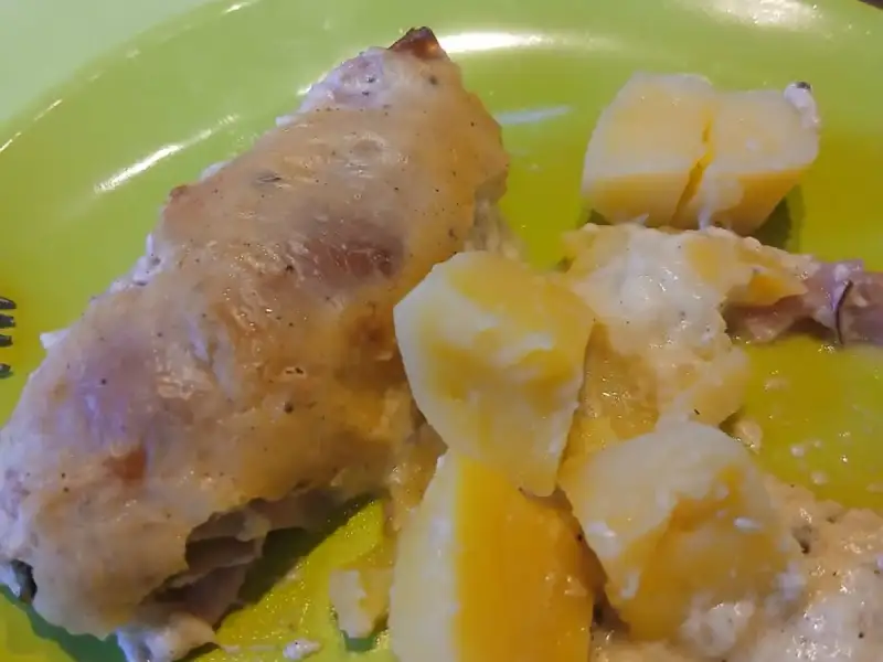 Roulades de poulet au jambon dorées au four avec des pommes de terre à la crème sur une assiette verte