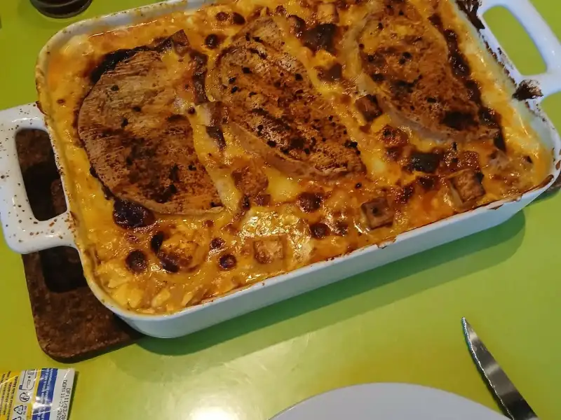 Tartiflette à la feta gratinée et dorée, servie dans un plat à gratin blanc