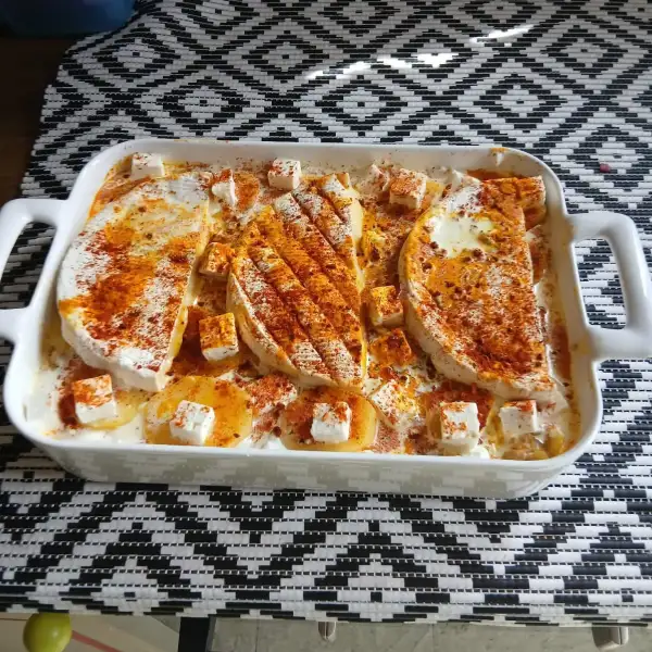 Tartiflette à la feta avant cuisson : pommes de terre, dés de feta et paprika dans le plat