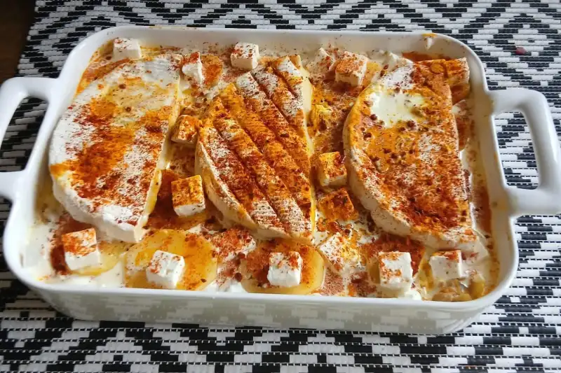 Tartiflette à la feta avant cuisson : pommes de terre, dés de feta et paprika dans le plat