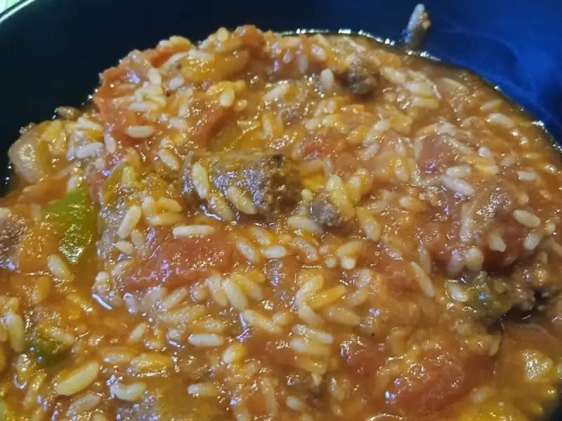 Diep bord gestoofde tomatenrijst met stukken rundvlees en paprika