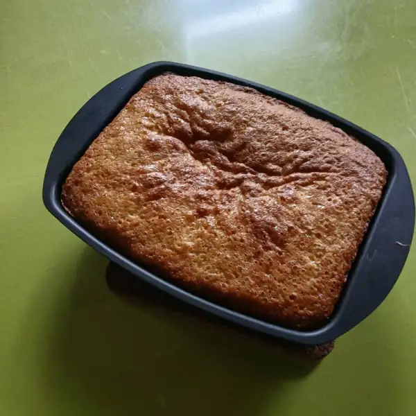 Goldbrauner, hoch aufgegangener Vierviertelkuchen mit Obst in einer rechteckigen Form